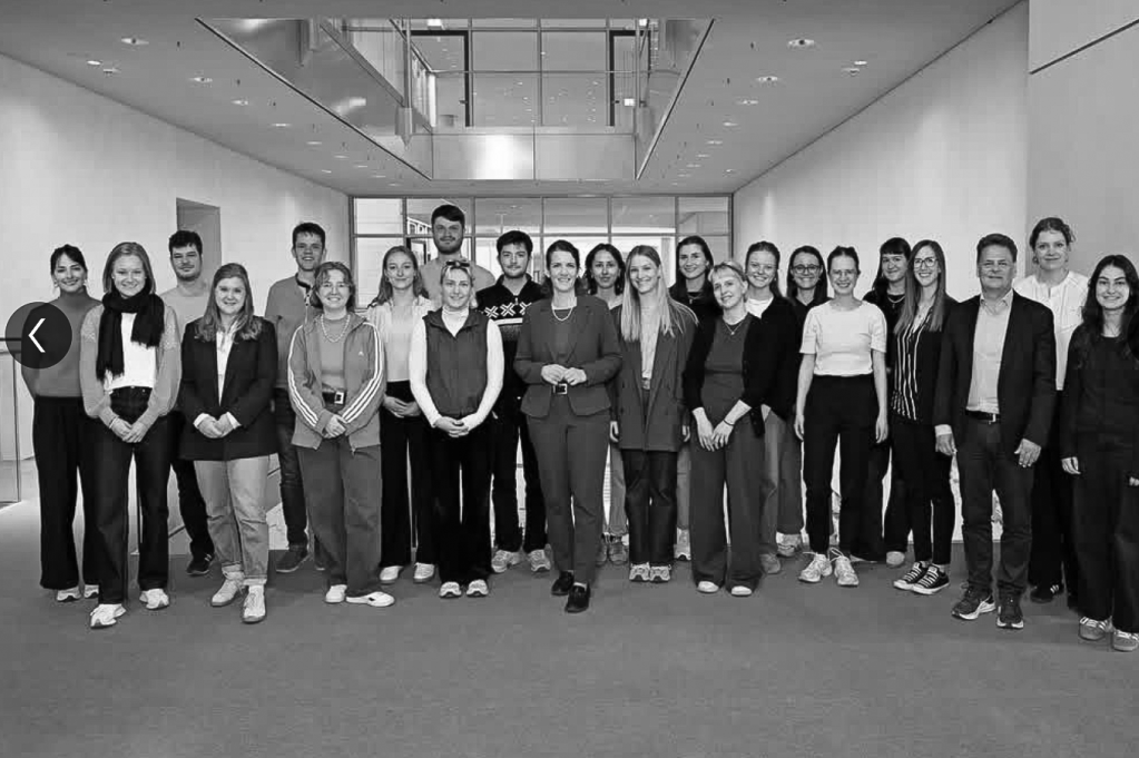 A group photo of a diverse class of students and an instructor standing in a modern academic environment, promoting collaboration and engagement in education.